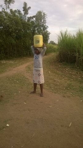 Magda carrying water-in the village. She had been accepted into the university but had no one to pay her school fees for university.